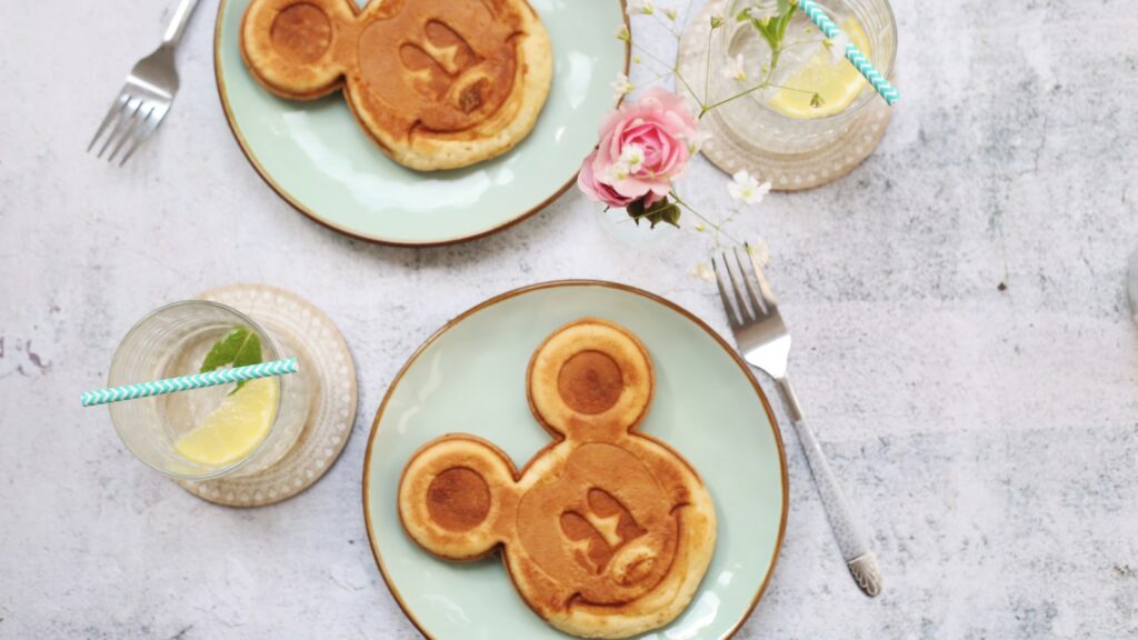 two Mickey Mouse pancakes on light green plates