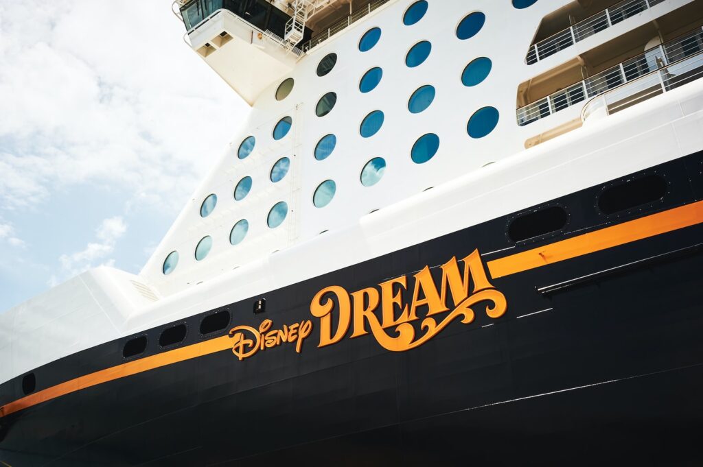 Side of white and black cruise ship reading "Disney Dream" in yellow