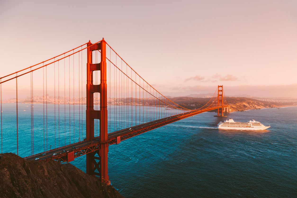 Beautiful panorama view of cruise ship passing famous Golden Gate Bridge with the skyline of San Francisco in the background