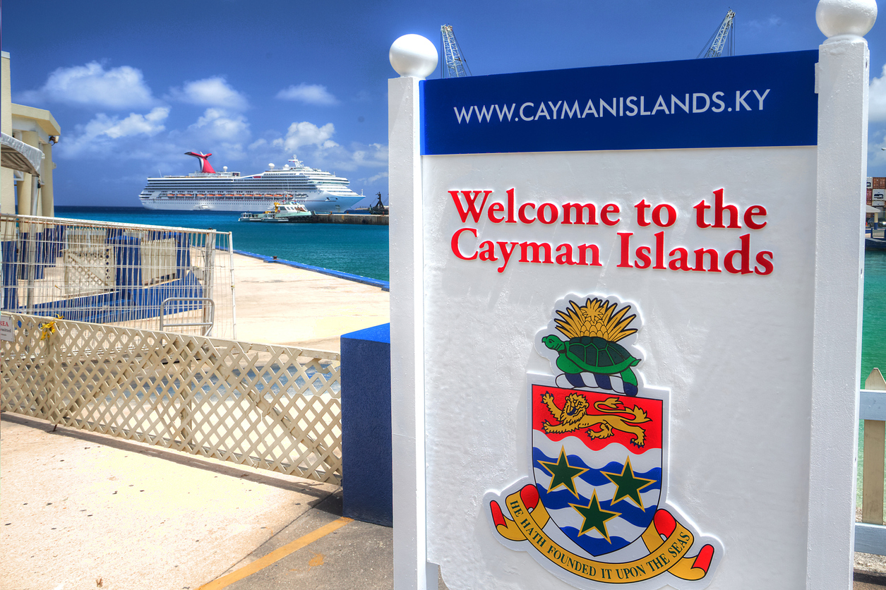 Cruise ship arrives in the background of a welcome sign in George Town, Grand Cayman
