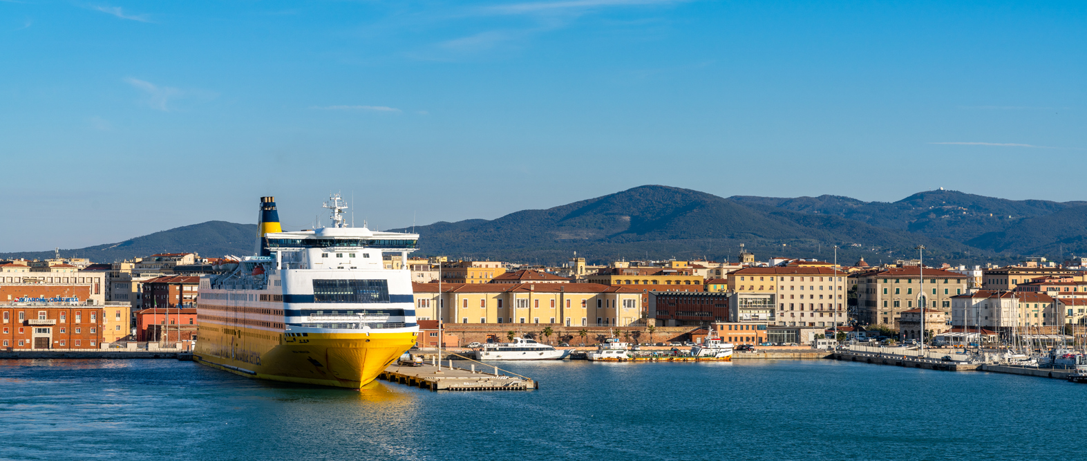 large passenger ferry in the port of Livorno with the old town and waterfront behind