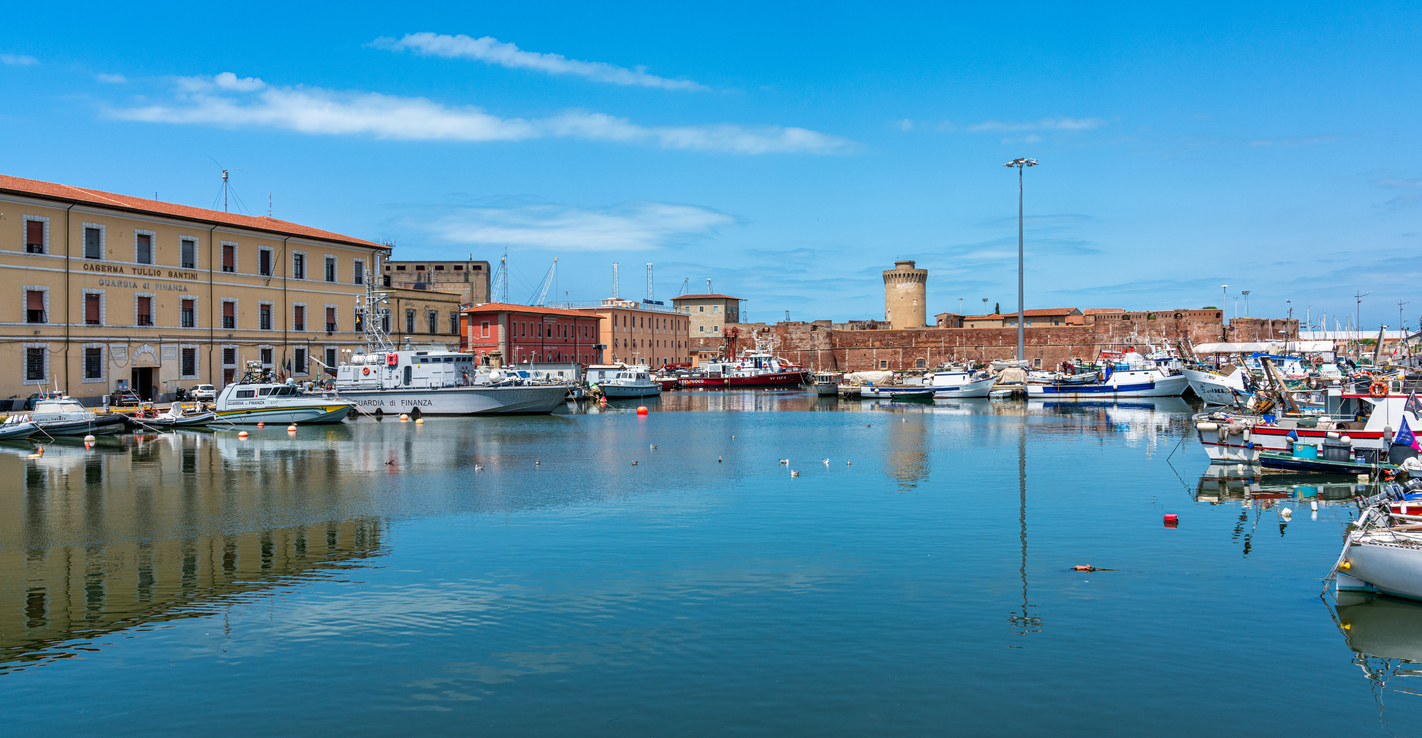Beautiful sight of the water with boats docked and the city of Livorno, Italy in the background
