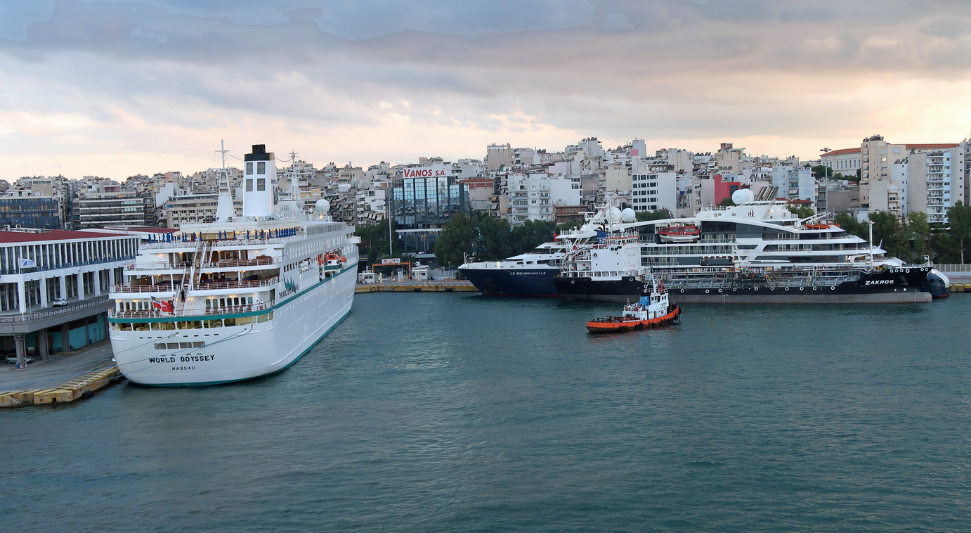 Large ships moored or docked at quayside jetties or piers in Port of Piraeus gateway to Athens. Outdoors on and autumn evening.