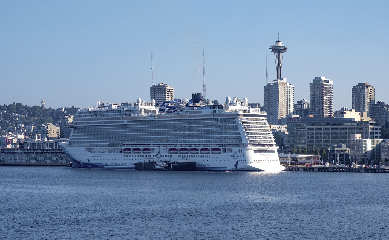 large cruise liner with Seattle skyline behind it.