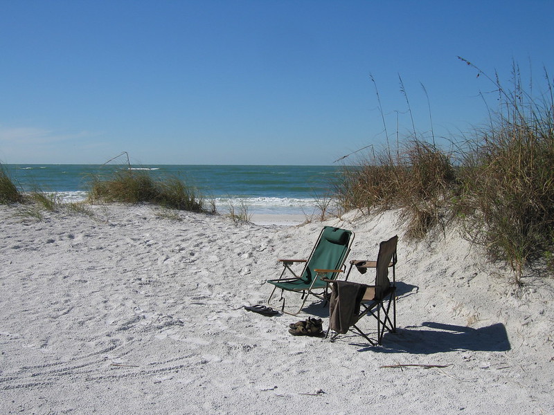 two chairs set up on the sand with the ocean in the background at the beach in Fort De Soto Park in Tampa Bay, FL