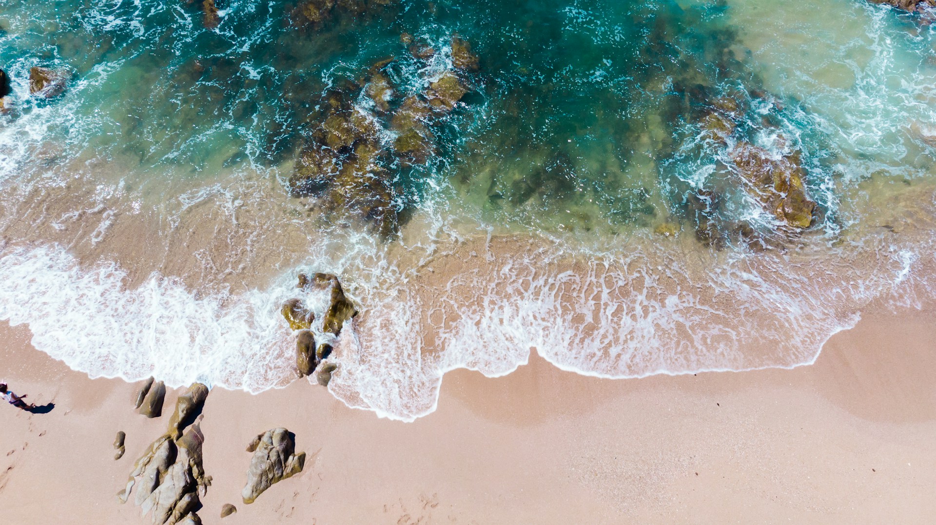 aerial view of sand, rocks, and the ocean at the beach in Mazatlan, Mexico
