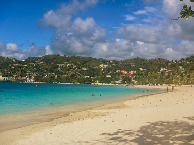 View of the sand, blue water, and the island in the background in Grand Anse beach in Grenada