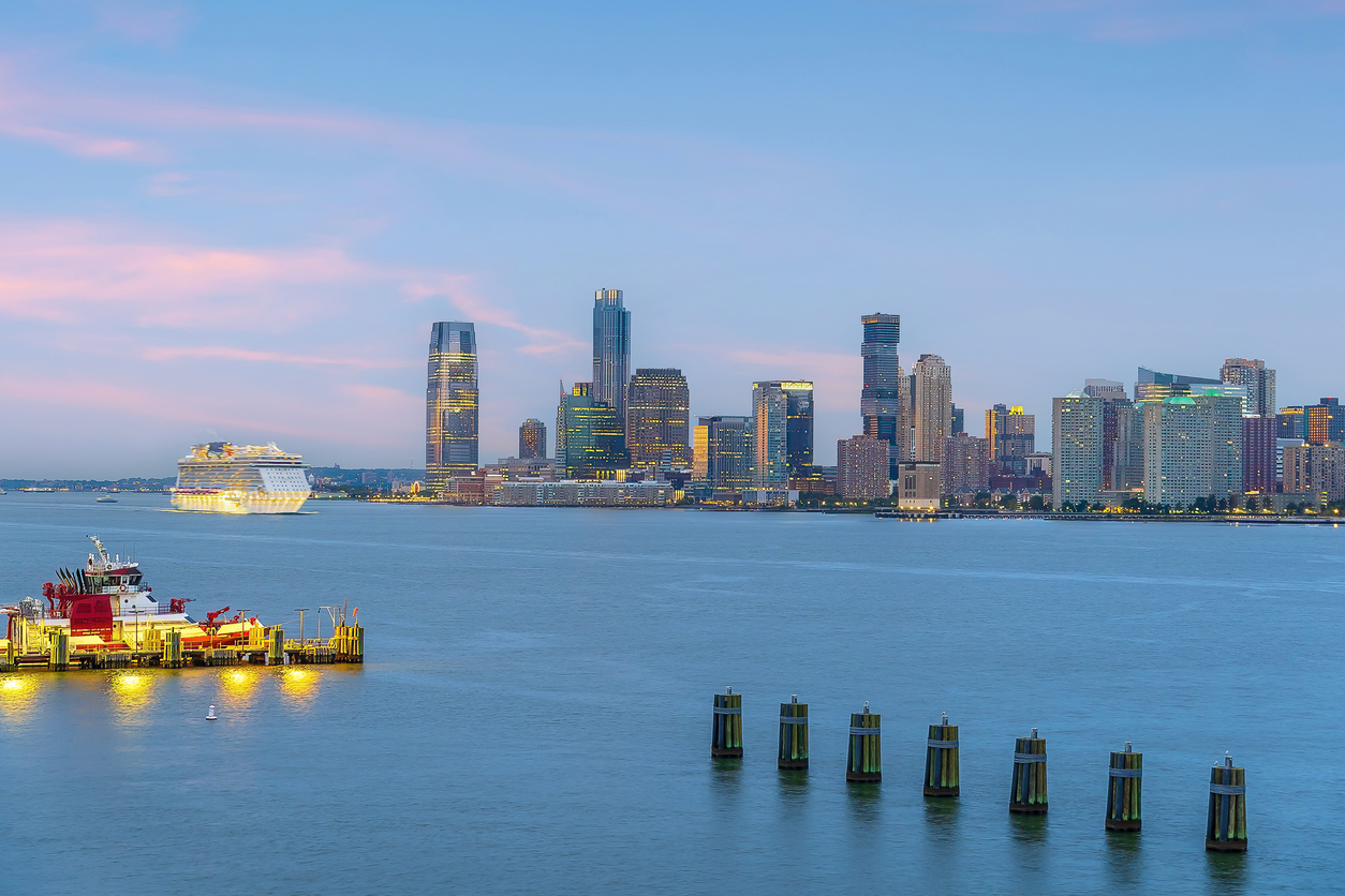 Cityscape of Jersey City skyline with a cruise ship arriving from Manhattan New York City at sunset